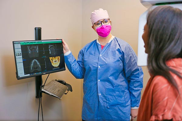 A dental assistant explaining an x-ray to a patient at Singing River Dentistry in Muscle Shoals, AL.