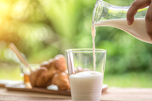  carafe of milk being poured into a glass