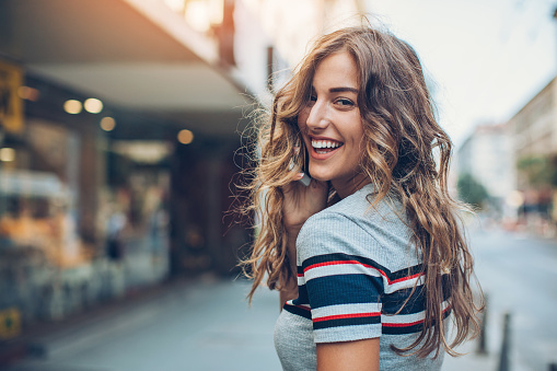 A college girl laughing over her shoulder after leaving a positive review for Singing River Dentistry in Florence, AL