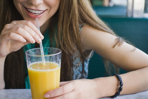 woman drinking orange juice with a straw