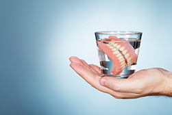 A person holding their dentures at Singing River Dentistry in Russellville, AL