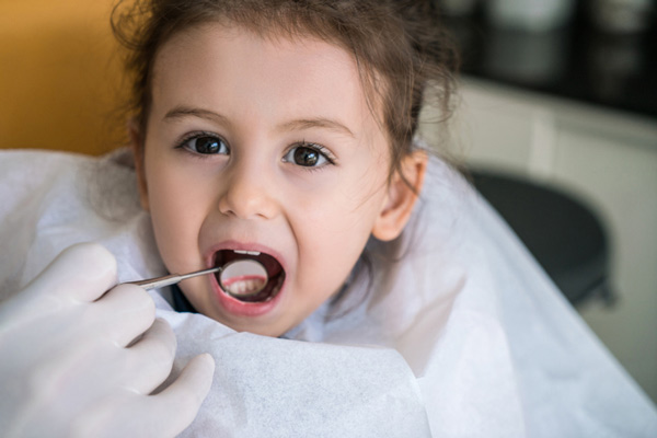 Dentist examining little girls teeth