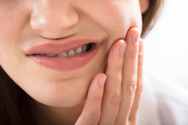 A woman with gum disease holding her jaw at Singing River Dentistry in Muscle Shoals, AL