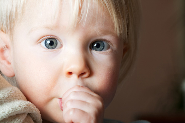 Little blonde boy sucking on his thumb