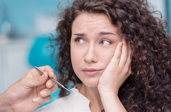 Woman holding cheek before tooth extraction at Singing River Dentistry in Muscle Shoals, AL