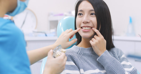 patient and dentist shown talking during an exam with patient pointing at her mouth