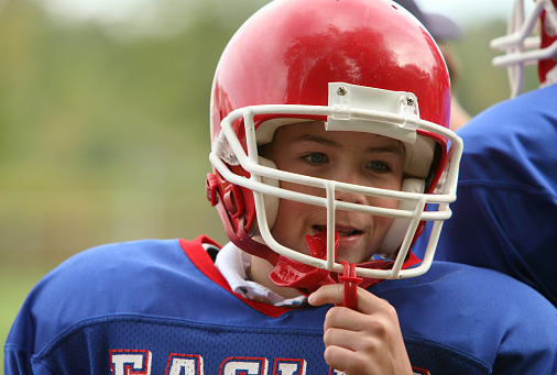 young football player with sports mouth guard and helmet