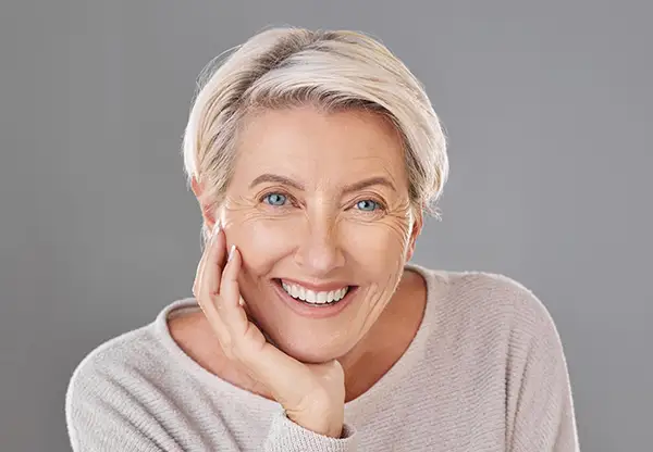 Mature woman with a confident smile, showcasing the results of cosmetic dentistry and rejuvenation treatments.